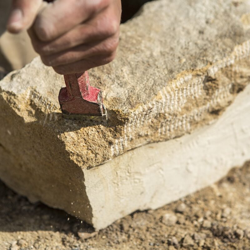 Traditional stonemasonry hand tools shaping natural stone